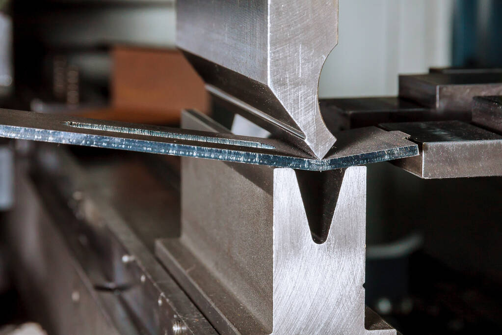 Bending sheet metal on a hydraulic machine at the factory. Bend tools, press brake punch and die. Close-up.